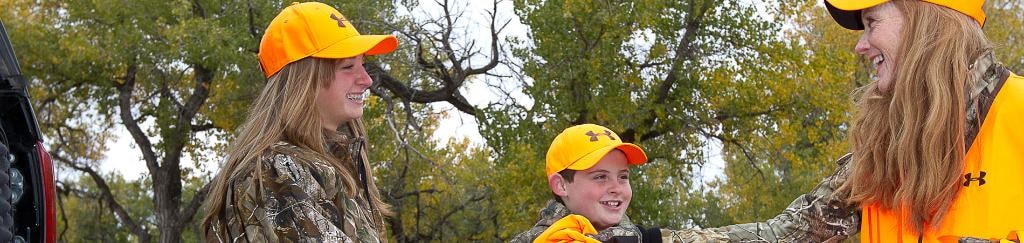 Family in camo and orange safety gear enjoying a hunter education course